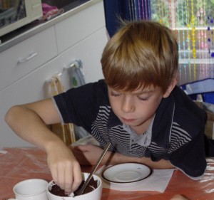 jongetje dat bezig is te roeren in een kom gesmolten chocolade